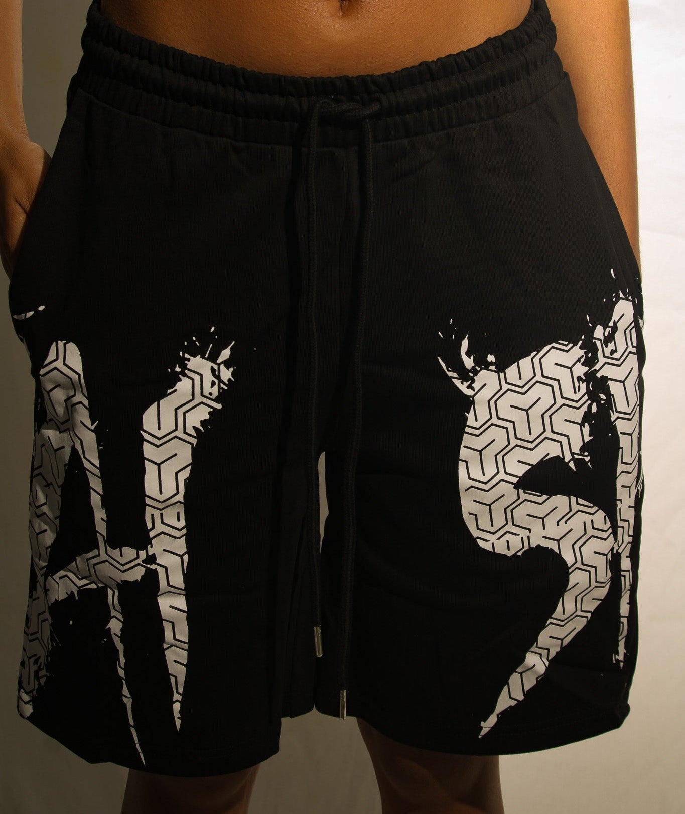Black shorts with white patterns worn by a person on a plain background